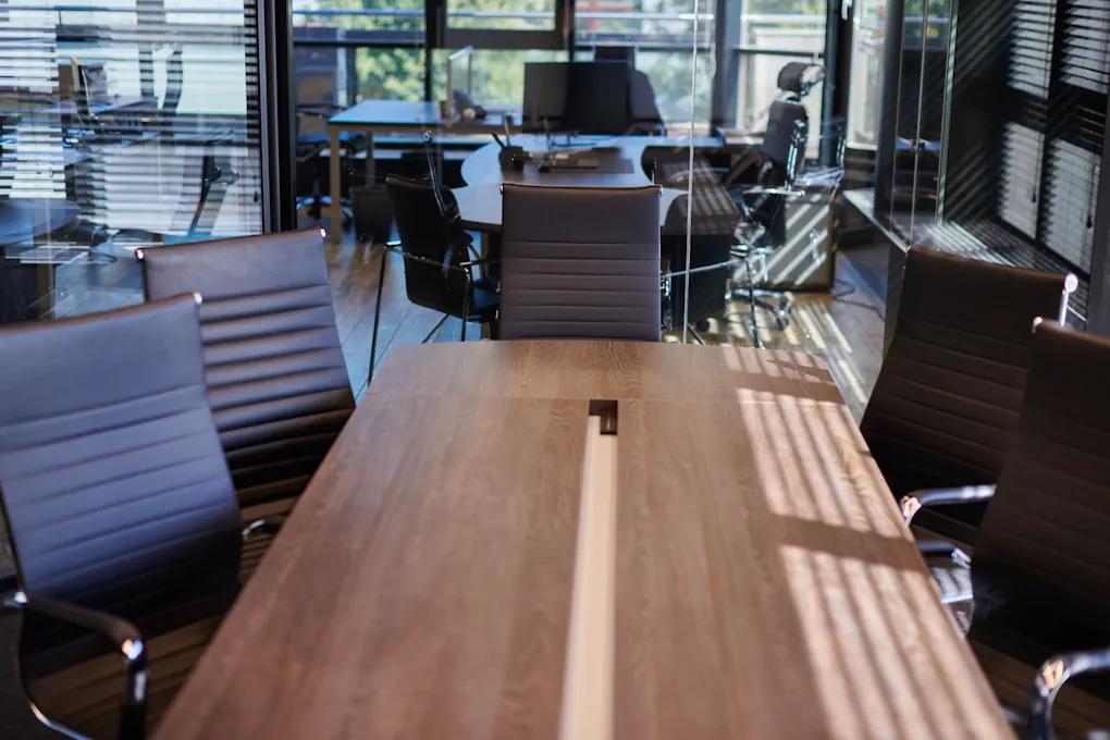 An association's boardroom between meetings — a long table, empty chairs and afternoon light through the blinds.